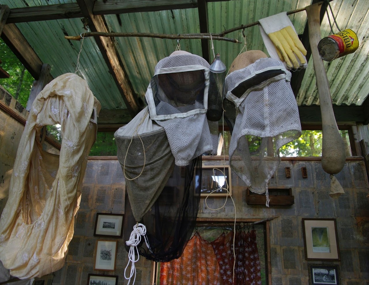 Beekeeping hats and veils hanging from a large wooden stick